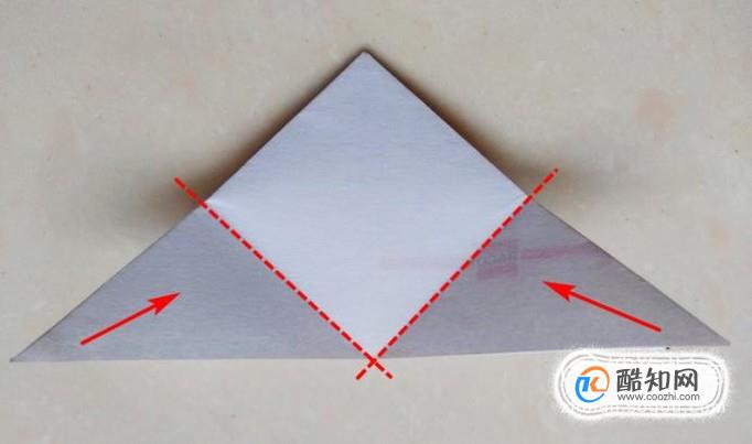 抓着三角形的两个尖角沿着虚线向中线对齐折叠,背面的三角形同样叠
