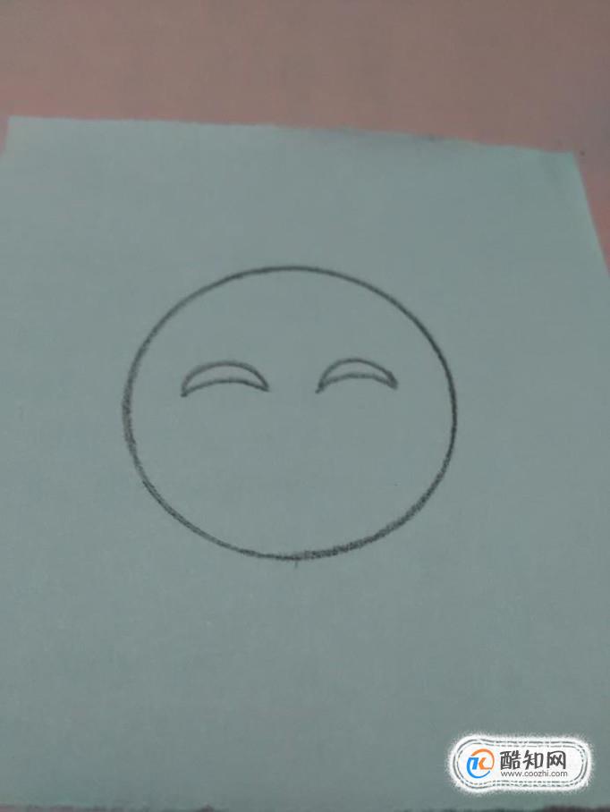 再用黑笔在脸上画两个向下弯的月牙形状,表示笑眯眯的眼睛.